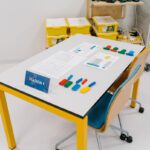 Station-1 setup for a Lean Manufacturing Simulation Game, displaying instruction sheets and colour-coded brick parts arranged for assembly.