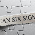 Puzzle background with a ripped paper strip labeled "Lean Six Sigma" – representing continuous improvement strategies such as Lean 5S and Six Sigma.