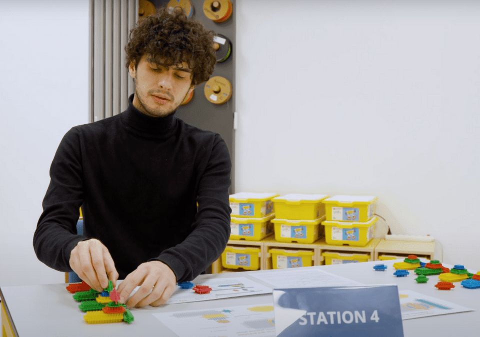 Participant engaged in a lean gaming simulation at Station 4 using colorful plastic blocks.