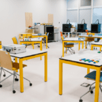 Lean Games for Training set up in a modern classroom with yellow tables and interactive materials.
