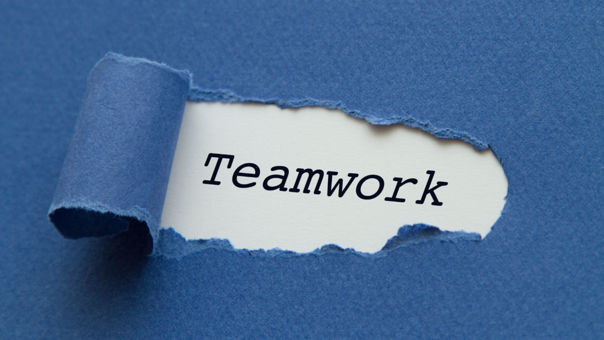 Torn paper revealing the word “Teamwork”, symbolizing the foundation of effective teamwork trainings.