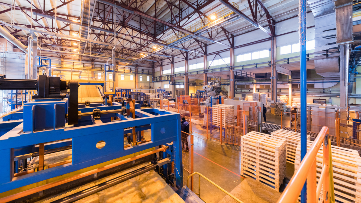 Modern production facility with neatly organized pallets, machinery, and open floor space — a visual example of lean manufacturing and the 5S methodology in practice. 