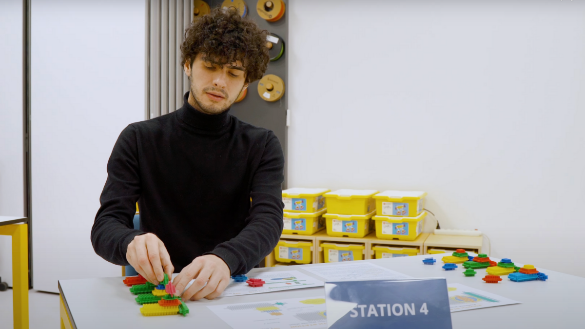 Participant engaged in a lean gaming simulation at Station 4 using colorful plastic blocks. 