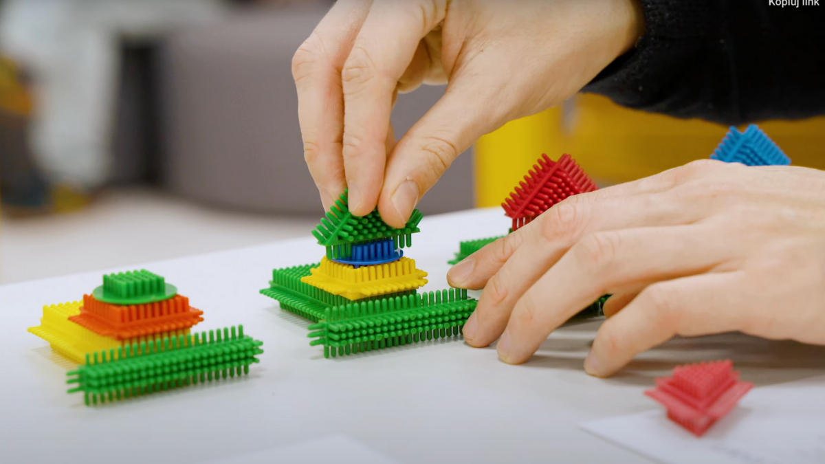 Hands assembling colorful blocks during training on lean manufacturing to simulate production processes.