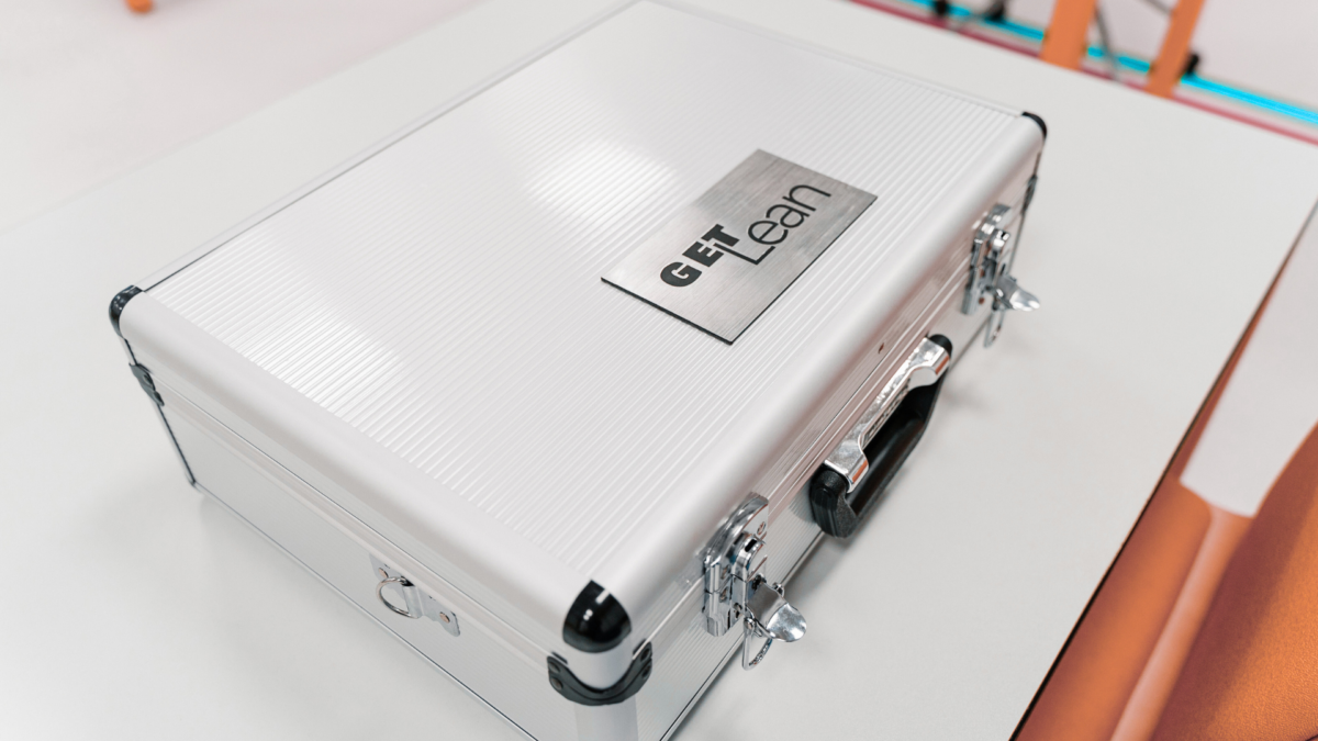 Silver case used in a lean production game training session, labeled "GET Lean." 