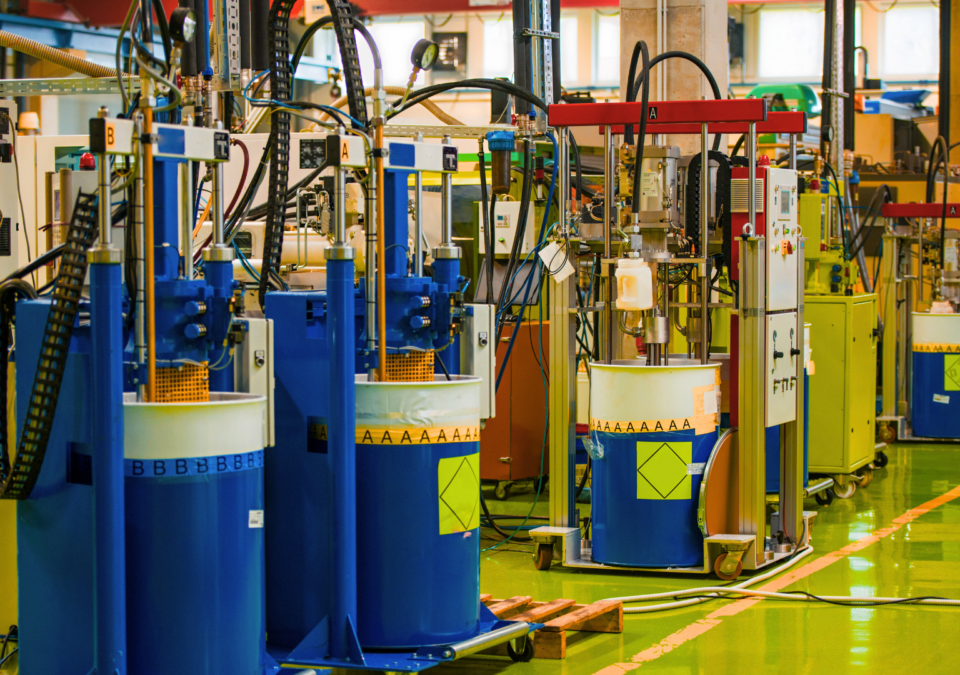 Automated dosing stations on blue drums in a clean 5S production cell organised around Lean Principles in Manufacturing.