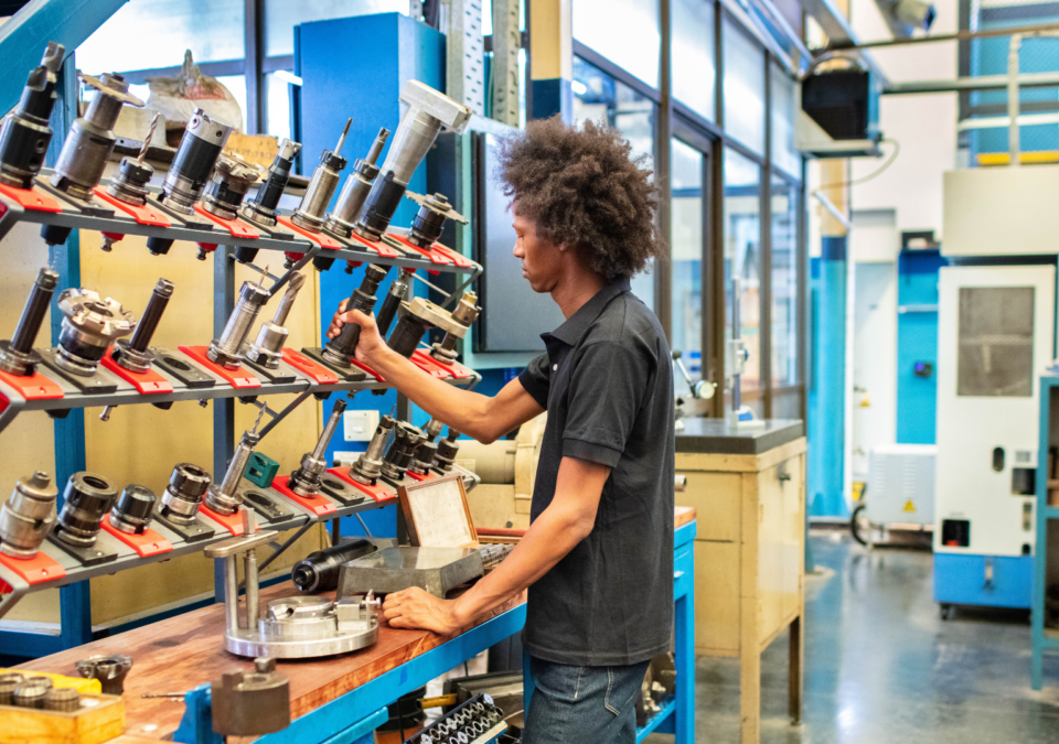 Worker applying Lean Process Improvement principles at a well-organized workstation in a manufacturing facility.