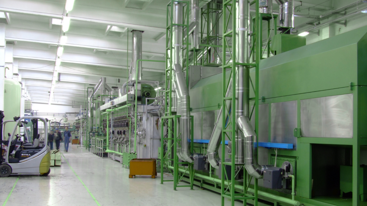 Modern production hall with green industrial machinery, illustrating lean methodology in practice.