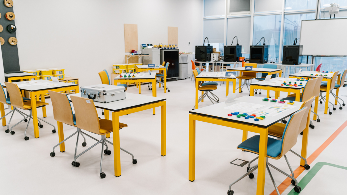 Lean Games for Training set up in a modern classroom with yellow tables and interactive materials. 