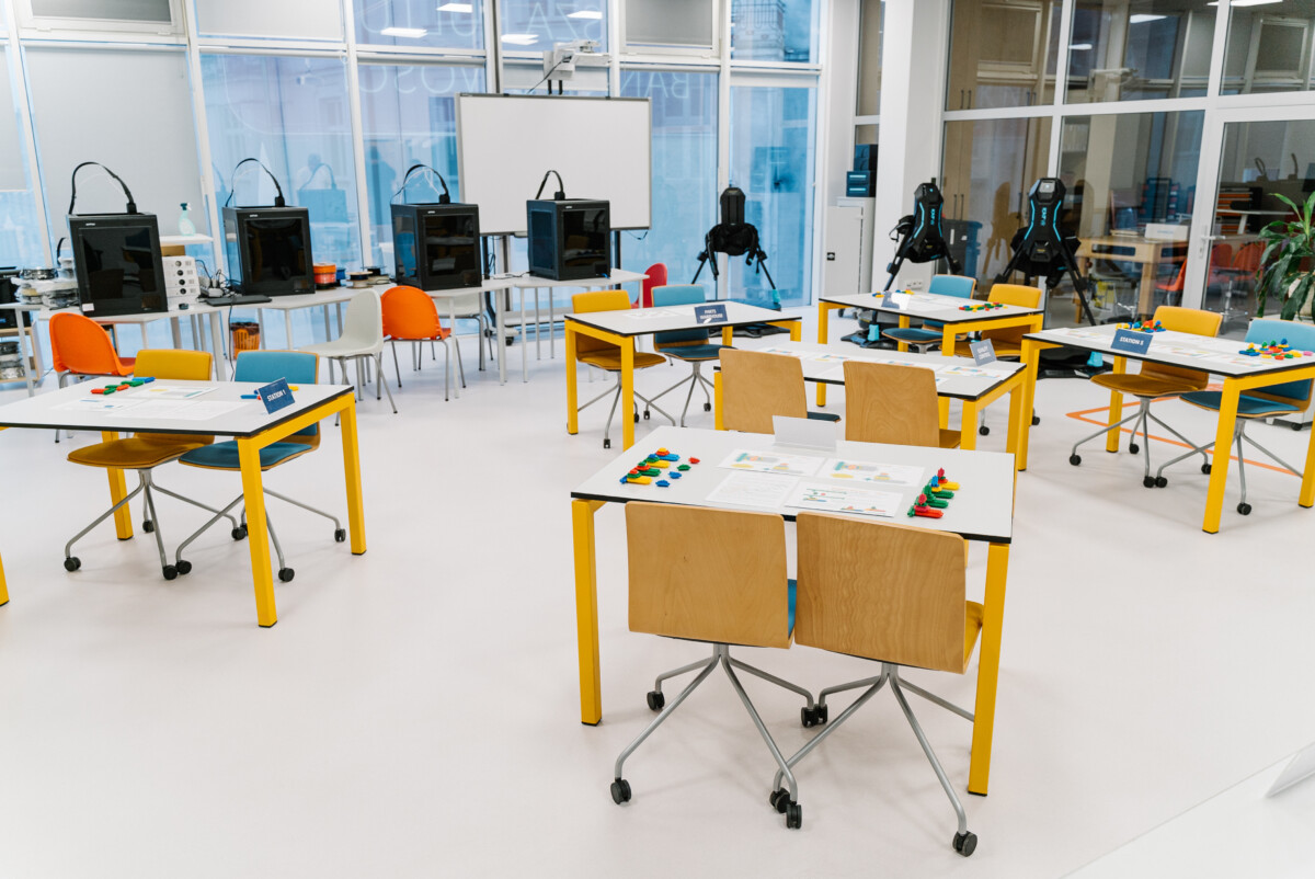 Training room setup with colorful materials and multiple stations prepared for Lean problem solving games focused on teamwork and process improvement.
